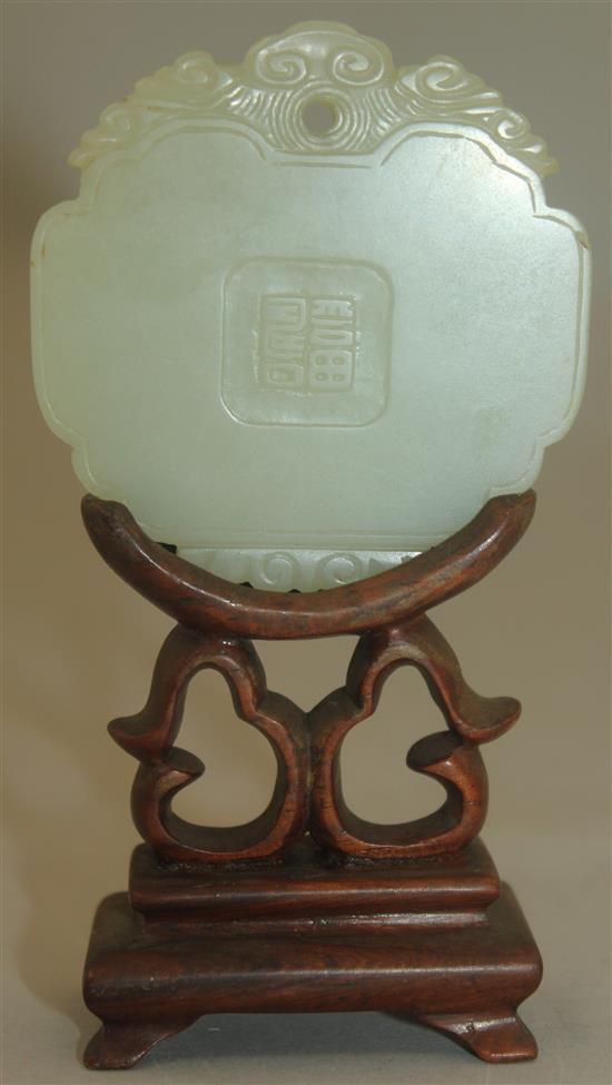 A Chinese pale celadon jade plaque, 19th century, 5.9cm, wood stand